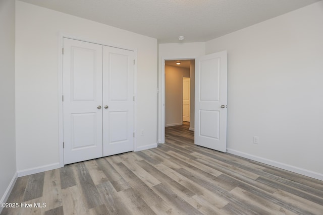 unfurnished bedroom with a closet, baseboards, and wood finished floors