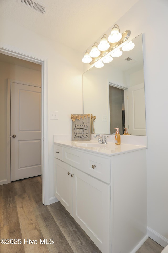 bathroom featuring vanity, wood finished floors, visible vents, and baseboards