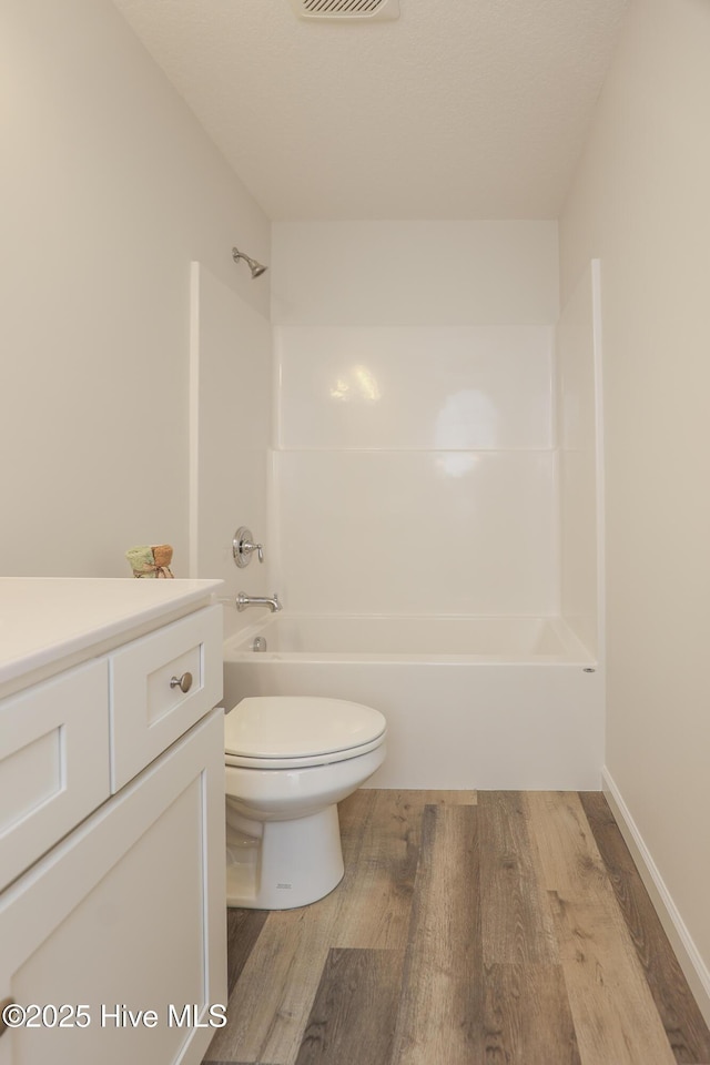 bathroom with visible vents, toilet, wood finished floors, vanity, and shower / washtub combination