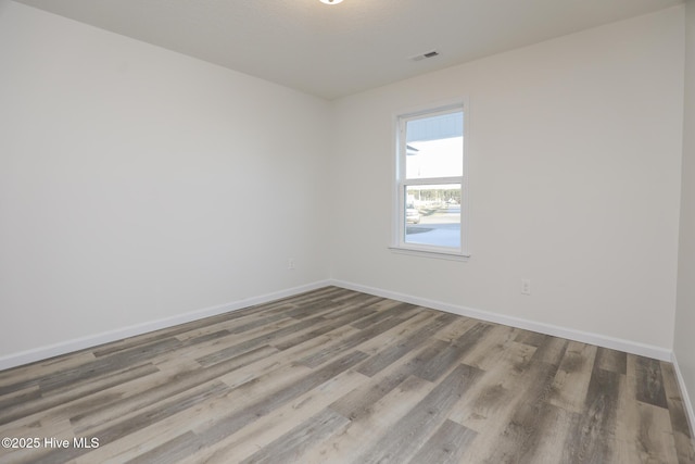 empty room featuring visible vents, baseboards, and wood finished floors