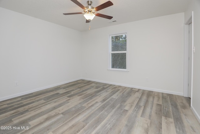 unfurnished room with a textured ceiling, wood finished floors, visible vents, and baseboards