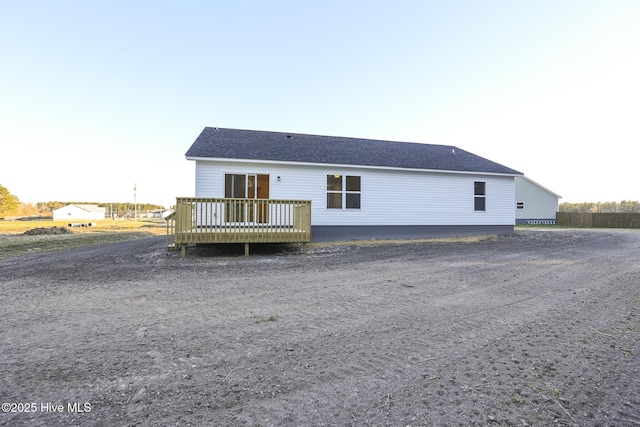 back of house featuring a shingled roof and a wooden deck