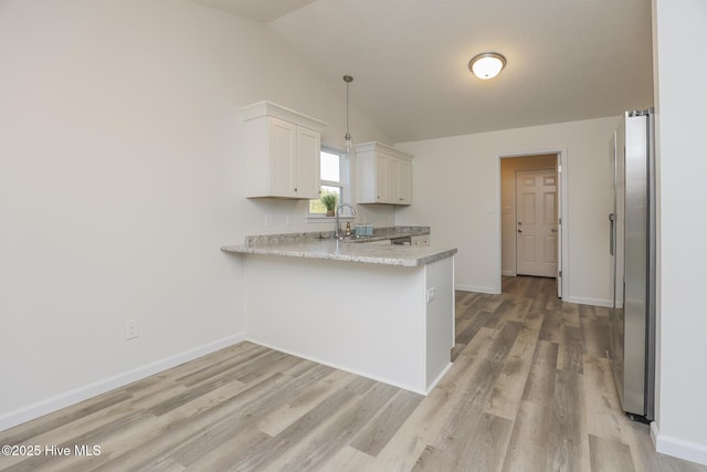 kitchen with lofted ceiling, a peninsula, light wood-style flooring, and baseboards