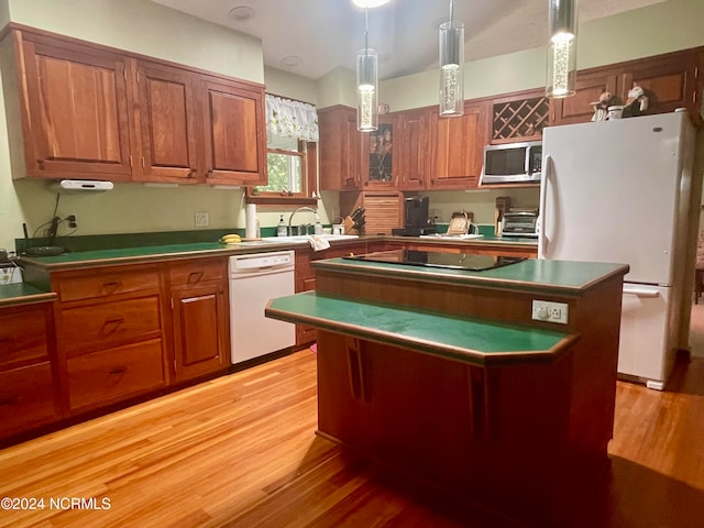 kitchen with light hardwood / wood-style flooring, hanging light fixtures, white appliances, and a kitchen island