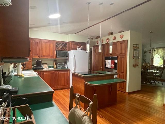 kitchen featuring light hardwood / wood-style flooring, appliances with stainless steel finishes, decorative light fixtures, and a center island