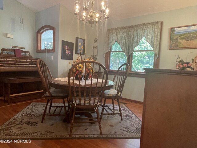 dining space featuring an inviting chandelier, hardwood / wood-style flooring, and lofted ceiling