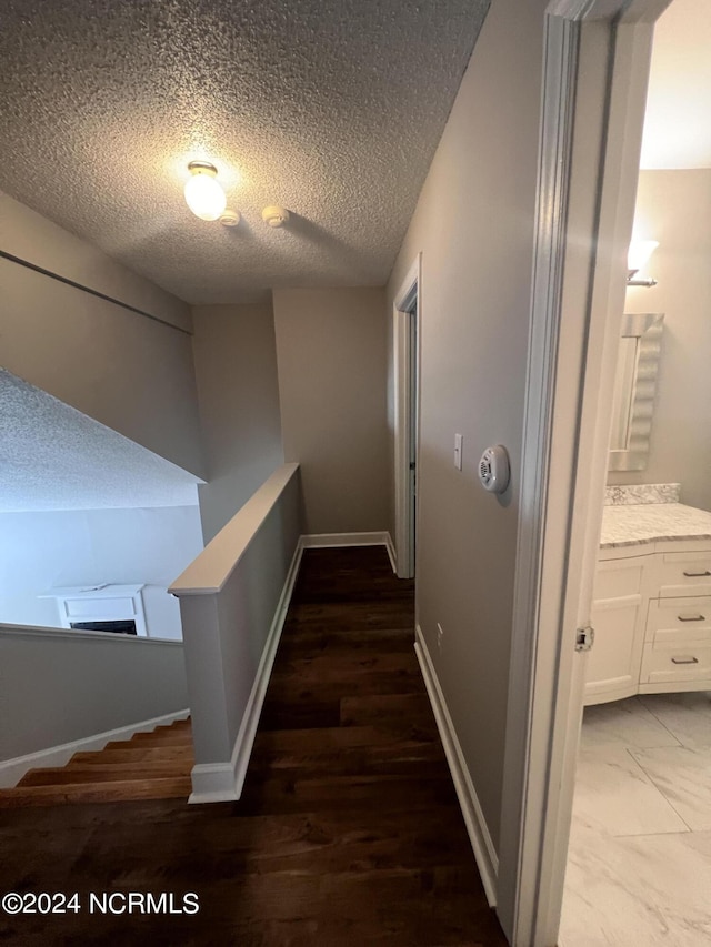 corridor with a textured ceiling and hardwood / wood-style flooring