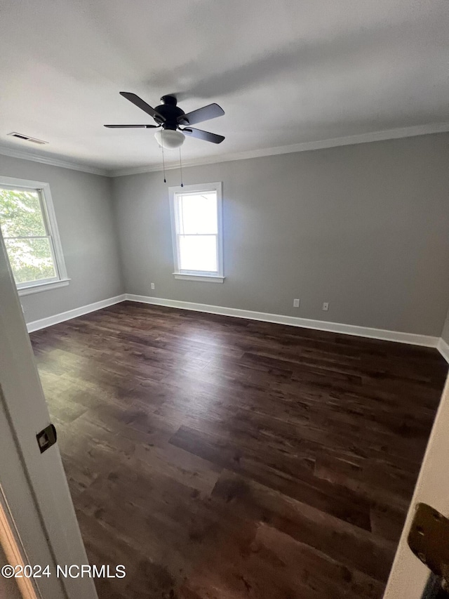 empty room with ornamental molding, ceiling fan, dark hardwood / wood-style floors, and plenty of natural light