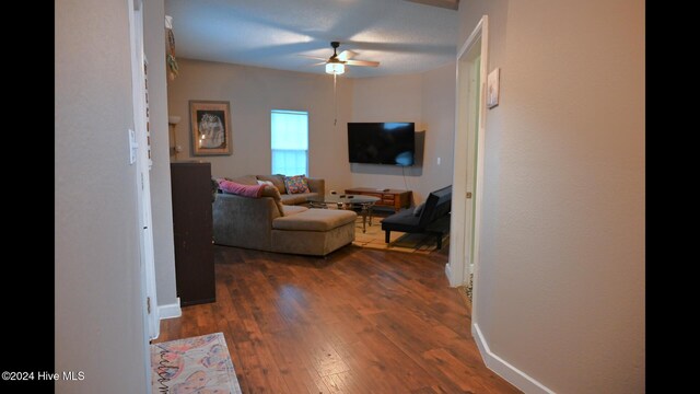 living room featuring ceiling fan and dark hardwood / wood-style flooring