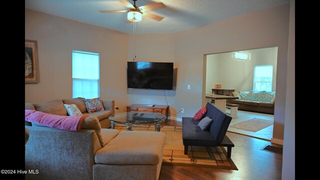 living room with dark hardwood / wood-style floors, ceiling fan, and a textured ceiling