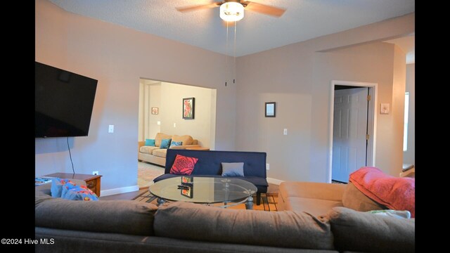 living room with a textured ceiling and ceiling fan