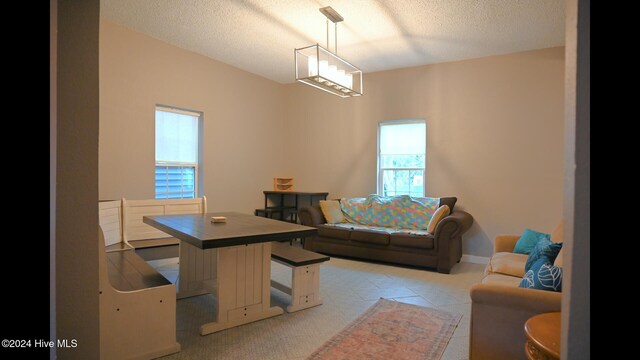 dining space with a textured ceiling and light carpet