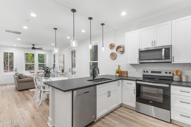 kitchen featuring appliances with stainless steel finishes, kitchen peninsula, white cabinetry, and hanging light fixtures