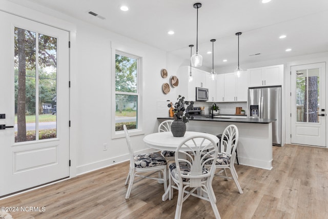 dining area with light wood-type flooring and a healthy amount of sunlight