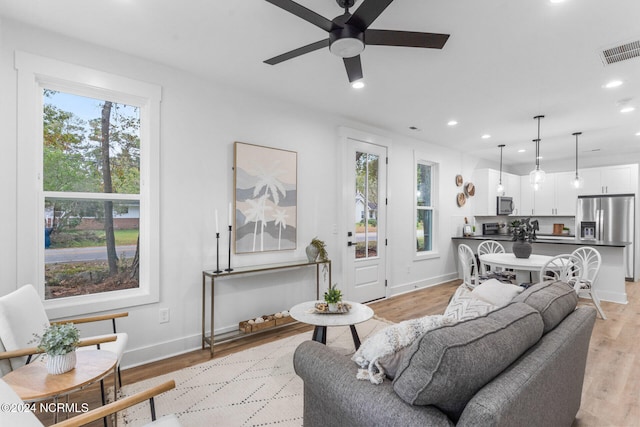 living room with a wealth of natural light, light hardwood / wood-style flooring, and ceiling fan