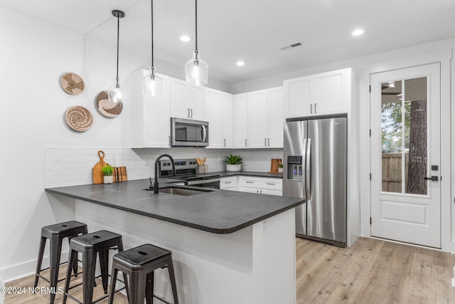 kitchen featuring stainless steel appliances, decorative light fixtures, kitchen peninsula, and white cabinets