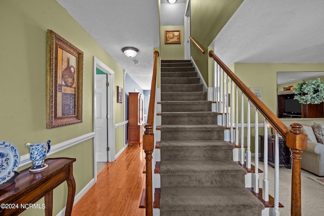 stairway featuring hardwood / wood-style floors and a textured ceiling