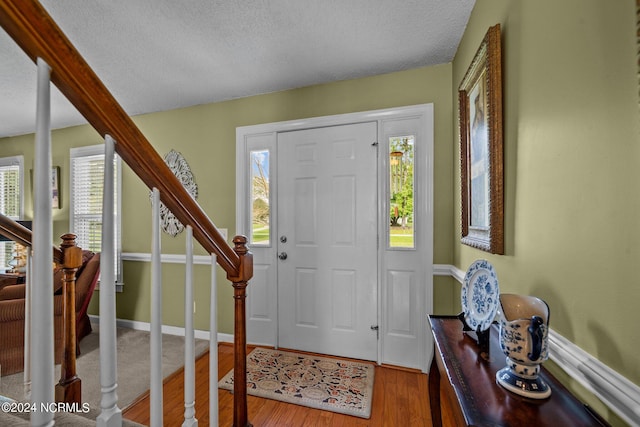 entryway with a wealth of natural light, hardwood / wood-style floors, and a textured ceiling