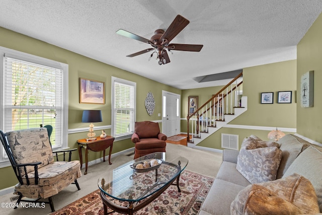 living room with ceiling fan, light colored carpet, and a textured ceiling