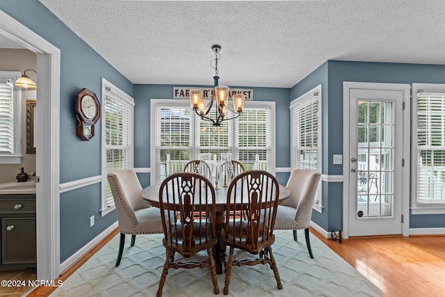 dining room with a notable chandelier, a wealth of natural light, light hardwood / wood-style floors, and a textured ceiling