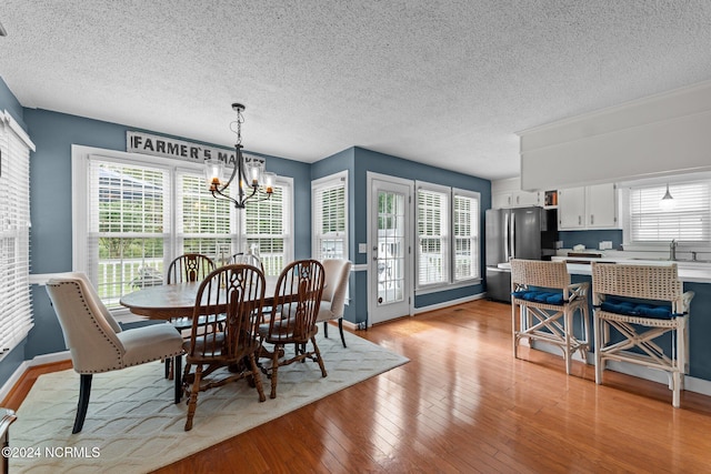 dining area featuring plenty of natural light, light hardwood / wood-style floors, an inviting chandelier, and a textured ceiling