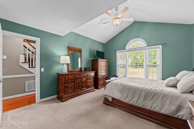 carpeted bedroom with vaulted ceiling, a textured ceiling, and ceiling fan