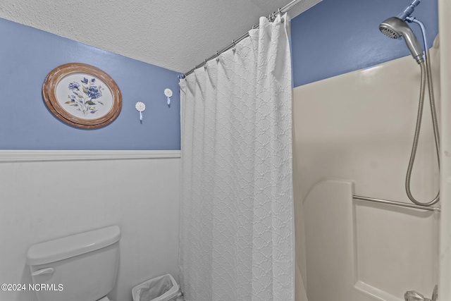 bathroom featuring a shower with curtain, a textured ceiling, and toilet