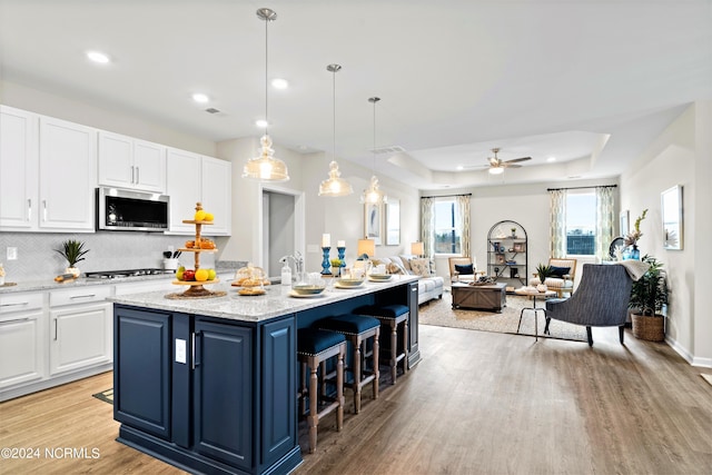 kitchen featuring white cabinetry, an island with sink, appliances with stainless steel finishes, and pendant lighting