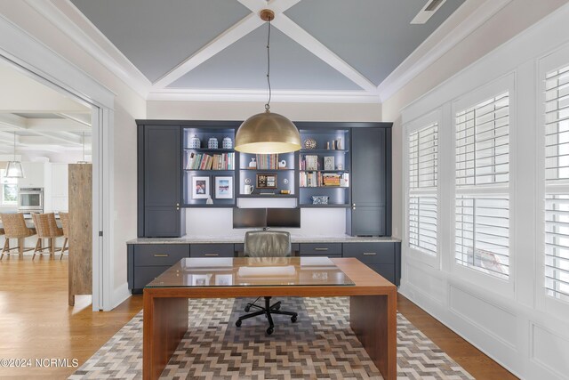 office area featuring a wainscoted wall, crown molding, visible vents, built in study area, and wood finished floors