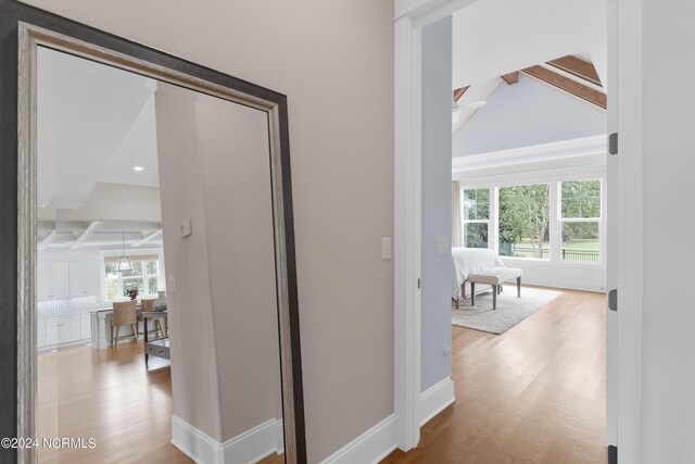 kitchen featuring stainless steel appliances, coffered ceiling, wood finished floors, white cabinetry, and decorative light fixtures