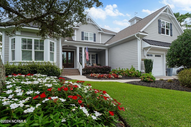 view of front of property with a shingled roof, french doors, an attached garage, and a front lawn