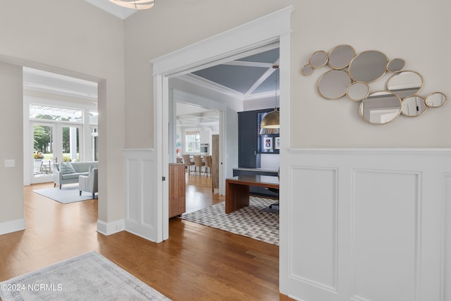 corridor with wainscoting, wood finished floors, and a wealth of natural light