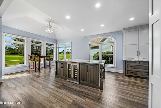 kitchen featuring dark wood-type flooring, an island with sink, beverage cooler, ceiling fan, and dark brown cabinetry