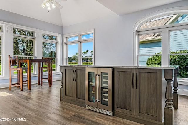 bar featuring wine cooler, hardwood / wood-style flooring, vaulted ceiling, dark brown cabinetry, and ceiling fan