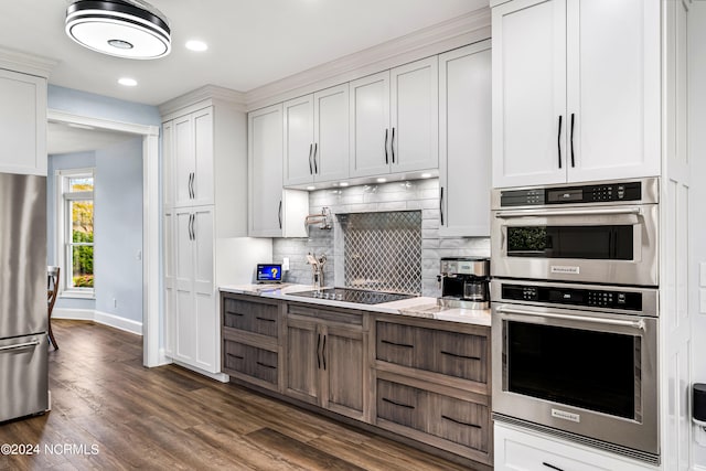 kitchen featuring dark wood-type flooring, white cabinetry, appliances with stainless steel finishes, light stone countertops, and decorative backsplash