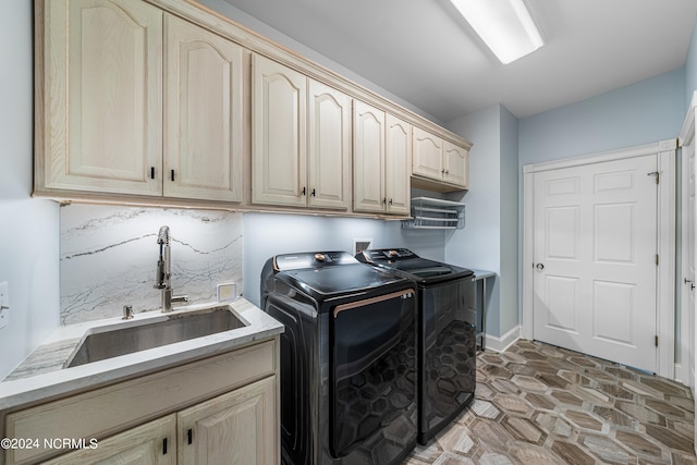 clothes washing area featuring washing machine and dryer, sink, and cabinets