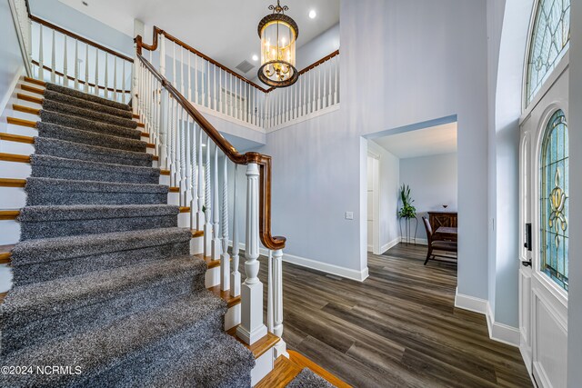 entrance foyer with an inviting chandelier, a towering ceiling, and dark hardwood / wood-style flooring