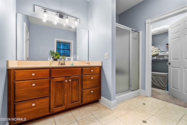 bathroom featuring tile patterned flooring, a shower with door, and vanity