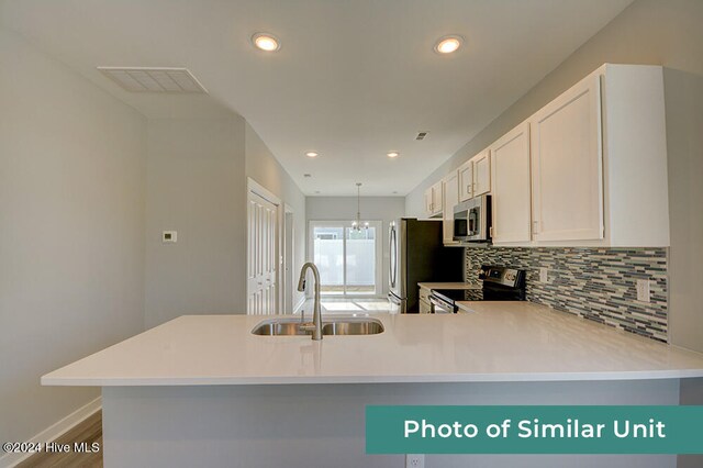 kitchen featuring light countertops, decorative backsplash, appliances with stainless steel finishes, white cabinets, and a sink