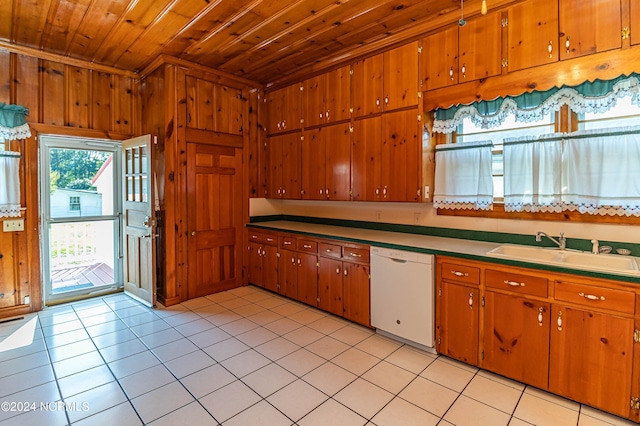 kitchen featuring light tile patterned flooring, wood walls, white dishwasher, wooden ceiling, and sink