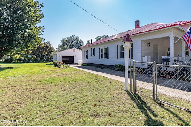 view of front facade with a garage, a front lawn, and an outbuilding