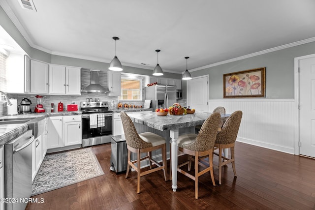 kitchen with a kitchen island, decorative light fixtures, wall chimney range hood, stainless steel appliances, and a kitchen bar