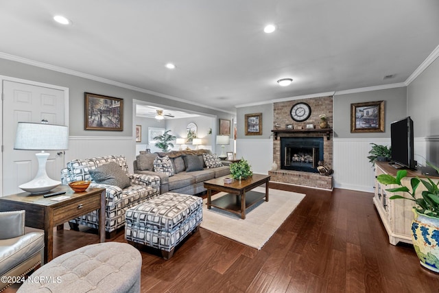 living room featuring a brick fireplace, ornamental molding, dark wood-type flooring, and ceiling fan