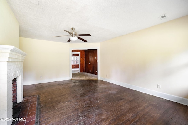 unfurnished living room featuring a fireplace, a textured ceiling, dark hardwood / wood-style flooring, and ceiling fan