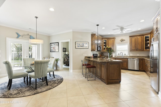 kitchen with pendant lighting, sink, appliances with stainless steel finishes, a kitchen breakfast bar, and dark stone counters