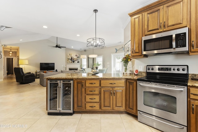 kitchen featuring stone countertops, hanging light fixtures, beverage cooler, and appliances with stainless steel finishes