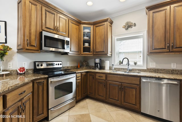 kitchen featuring sink, light tile patterned floors, dark stone countertops, stainless steel appliances, and ornamental molding