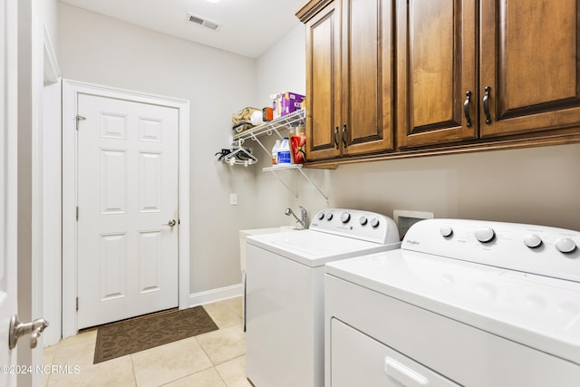 washroom featuring cabinets, light tile patterned floors, and washer and clothes dryer