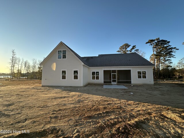 back house at dusk featuring a patio area