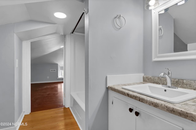 bathroom with wood-type flooring, vanity, lofted ceiling, and shower / bathtub combination